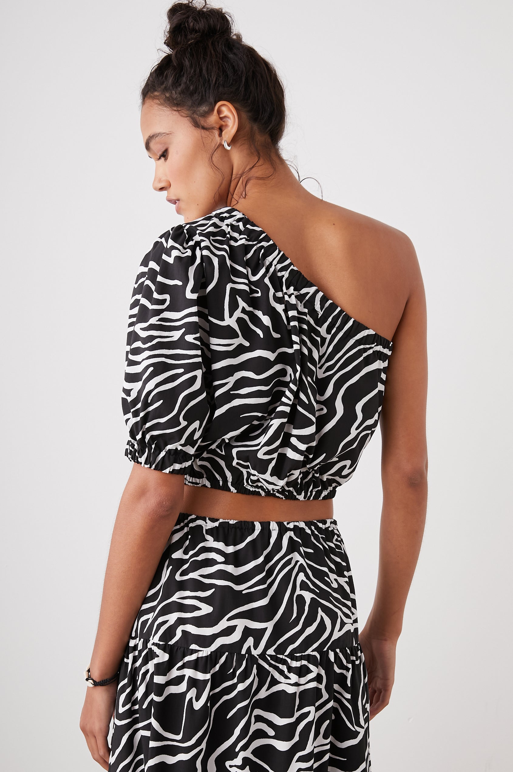 Evy Crop Top with an Asymmetrical Neckline, One Short Sleeve, and One Sleeveless, an Elasticized Hem and Cuff in Contour Lines Colorway, White Curves on Black - Back View Featured on Model 