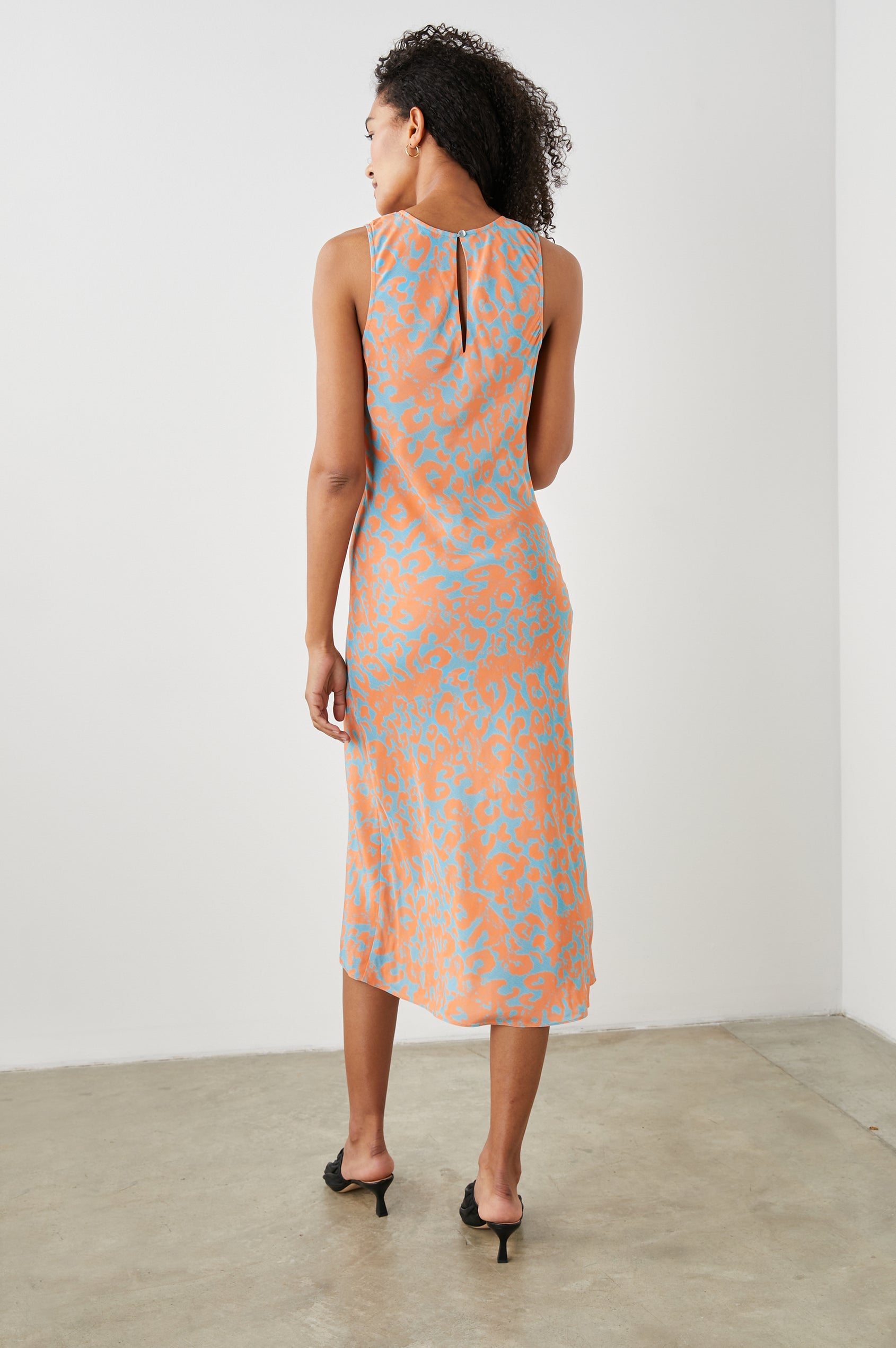 Gabriella Sleeveless Midi Dress with a Crew Neck, a Left Thigh Side Slit, a Ruched Drawstring on the Left Side and a Keyhole Button Closure at the Back in Orange Diffused Cheetah Colorway, Orange Spots on Blue - Back Full Body View Featured on Model 