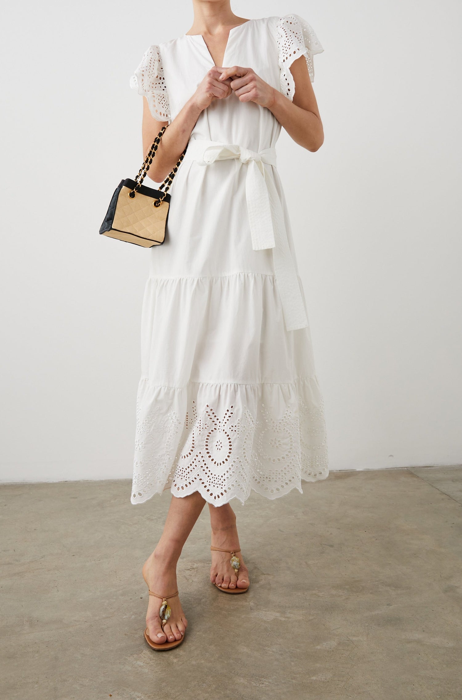 Gia Short-Sleeve Midi Dress with Flutter Sleeves, a V Neck, a Fabric Tie at the Waist, a Tiered Skirt and Eyelet Detail on the Sleeves and Hem in White Colorway - Front Full Body View Featured on Model