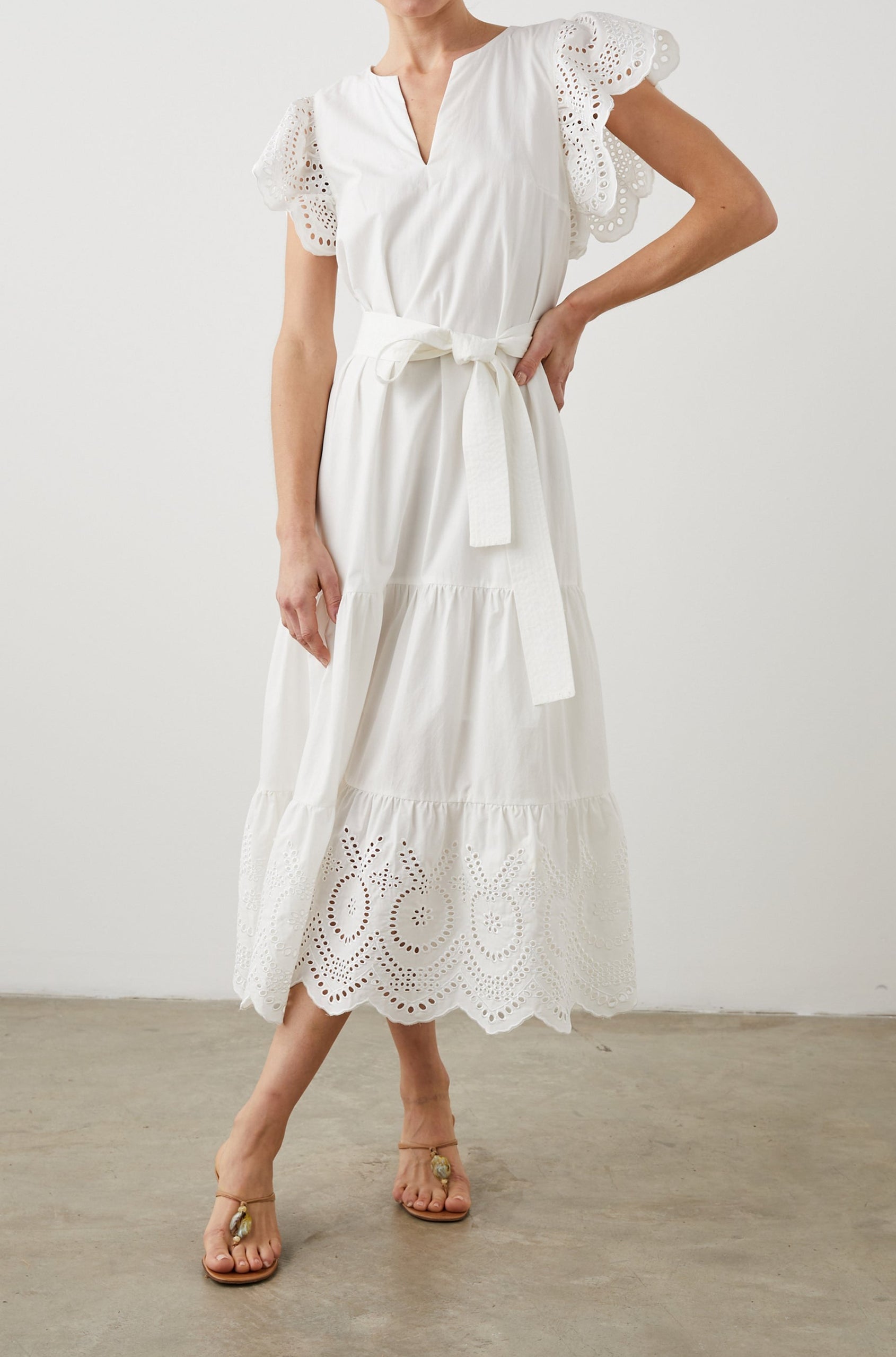 Gia Short-Sleeve Midi Dress with Flutter Sleeves, a V Neck, a Fabric Tie at the Waist, a Tiered Skirt and Eyelet Detail on the Sleeves and Hem in White Colorway - Front Full Body View Featured on Model