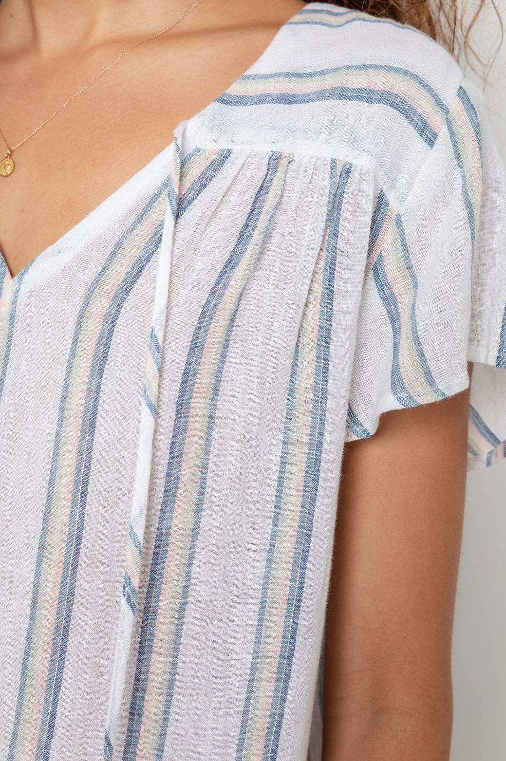 Viera Short-Sleeve Top with a V Neck with a Tie and Flutter Sleeves in Ryland Stripe Colorway, Muted Blue, Pink, Cream and Green Vertical Stripes on White - Front View Featured on Model 